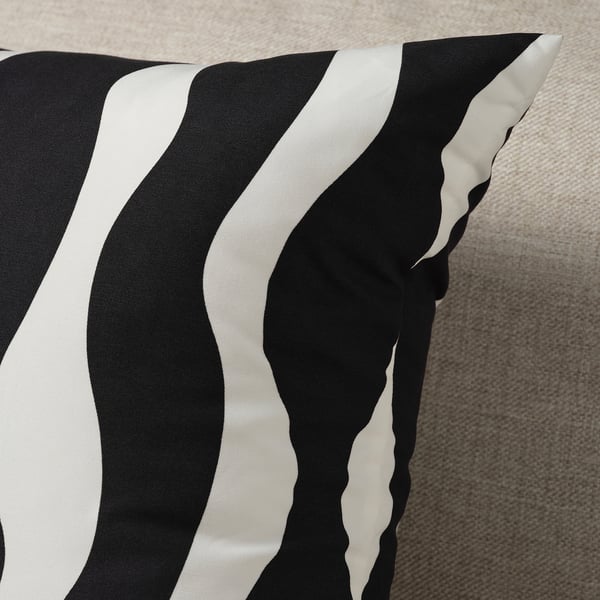 Black and white striped pillow on a grey surface, likely sofa or bed.