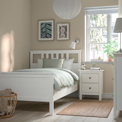 Cosy bedroom with HEMNES bed, bedside table, dresser, pillows, blanket, lamp, plants, art, and rug.