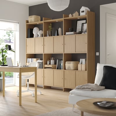 Modern office space with LÅDMAKARE light wood shelves, decor, white couch, desk, and large window.