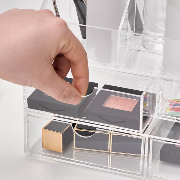 Hand opening clear acrylic storage drawer, holding makeup boxes, showcasing organised storage solution.