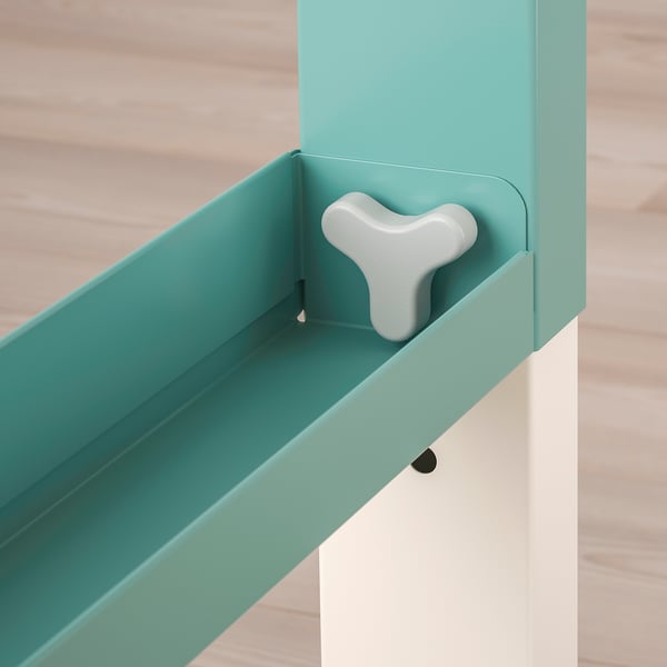 Turquoise cable organiser with white handle on wooden floor.