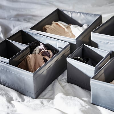 SKUBB grey organiser boxes store socks and accessories, folded on bed.