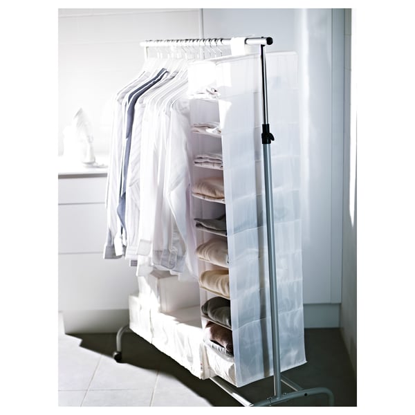 A white SKUBB storage unit with multiple shelves holding folded clothes. Its made of recycled polyester and hangs on a rack.