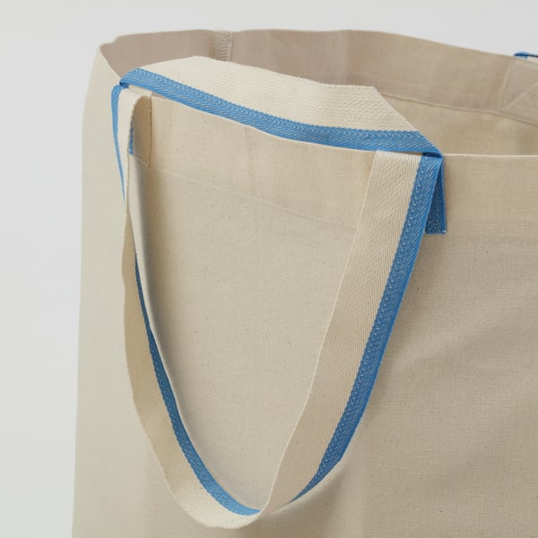 Close-up of well-stitched, blue-edged canvas tote bag, showcasing durable design.