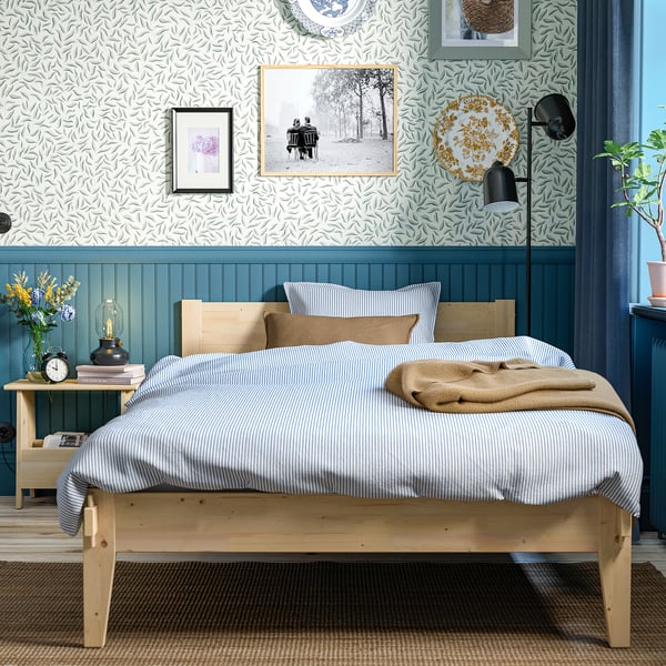 Cosy bedroom with TAXÅSKLINT pine bed, blue/white linens, teal panels, art, bedside vase & books.