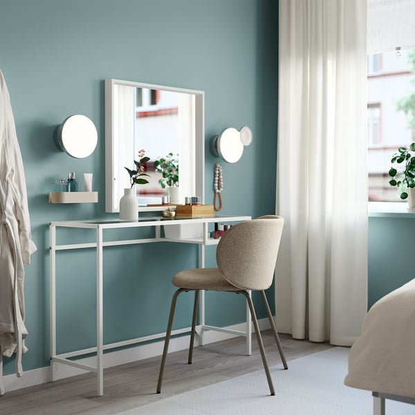 White VITTSJÖ desk with glass top & beige chair. Teal wall, mirror, wall lights - minimal, functional.