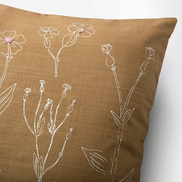 Floral cushion cover with hand-embroidered details on brown cotton. White floral designs and french knots, showcasing quality craftsmanship.
