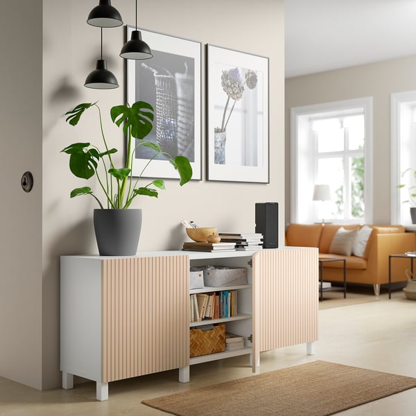 Modern living room with BESTÅ sideboard, plant, pendant lights, art, orange sofa.