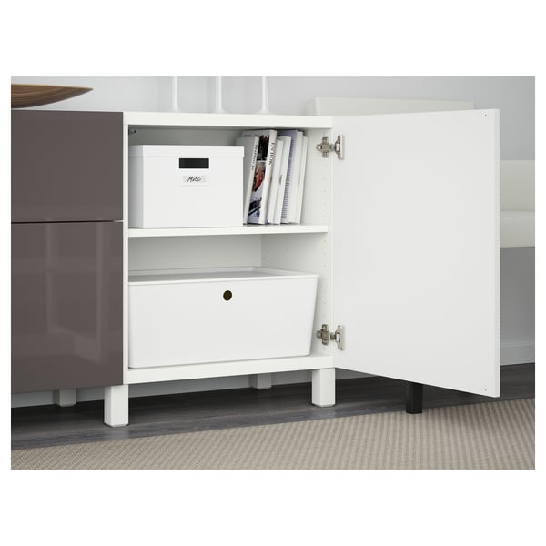 White BESTÅ unit with open drawer and shelf holding a box and books, featuring soft-close drawer and door mechanisms.