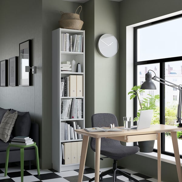 Modern green home office with a BILLY white bookshelf, black chair, wooden desk, and black and white chequered floor.