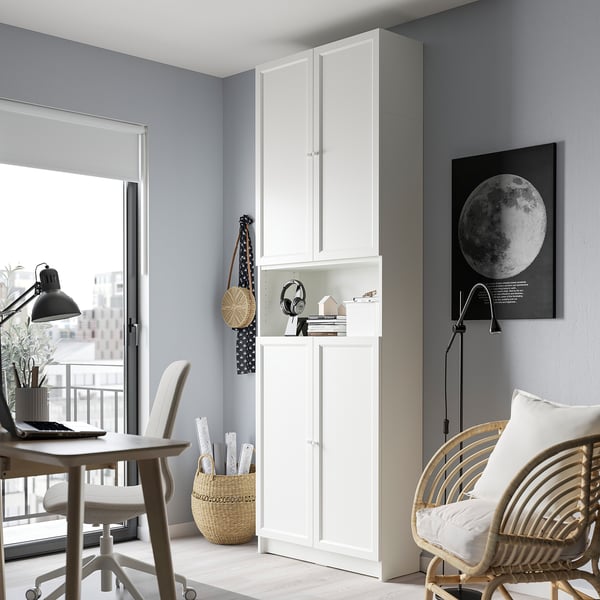 Modern home office with BILLY bookcase, desk, wicker chair, natural light, laptop, and decor.