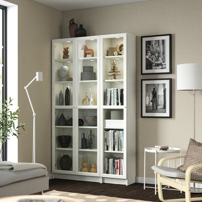 White BILLY bookcase in living room filled with decor and books beside large window.