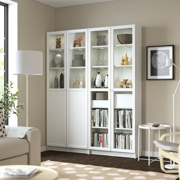 White BILLY bookcase in living room, tall & wide, holding books & decor, positioned near sofa & lamp.