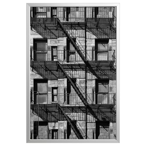 Black and white framed a multi-story building with fire escape staircases, capturing urban architecture.