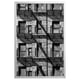 Black and white framed a multi-story building with fire escape staircases, capturing urban architecture.