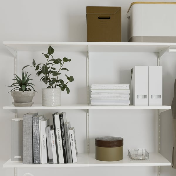 White wall shelves with potted plants, books, and storage boxes.