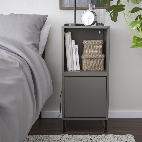 Minimalist bedside table with books & baskets, next to a bed.