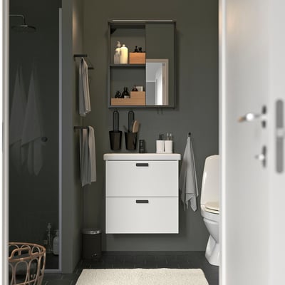 Modern bathroom with ENHET cabinet, sliding mirror, grey towels, toilet, and bath mat.