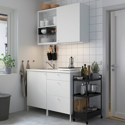 Modern ENHET kitchen with white cabinets, steel sink, black trolley, and utensils for efficient design.