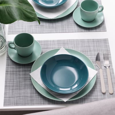 Table setting with blue-green plates, cups, napkins, and cutlery on grey placemats.