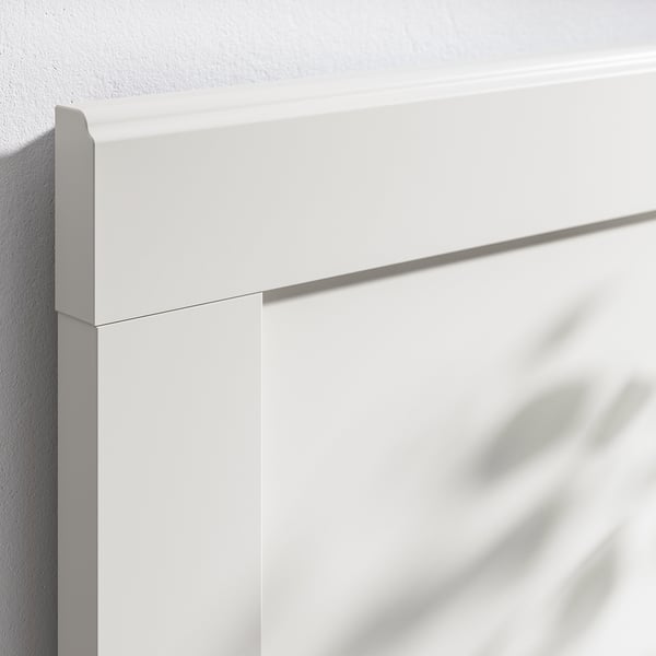Close-up view of a white, sleek, modern bed frame corner, showing clean lines and quality finish.