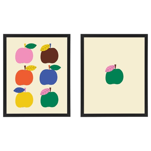 Two framed art prints. Left frame has colourful apples, right one is green apple with leaves. Black frames, cream background.