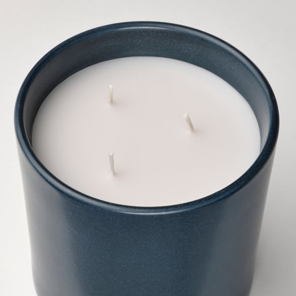 A cylindrical blue candle jar with three unlit wicks, smooth finish, minimalist design.