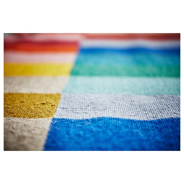 Close-up of handwoven HALVED rug in colourful stripes, mostly blue and white.