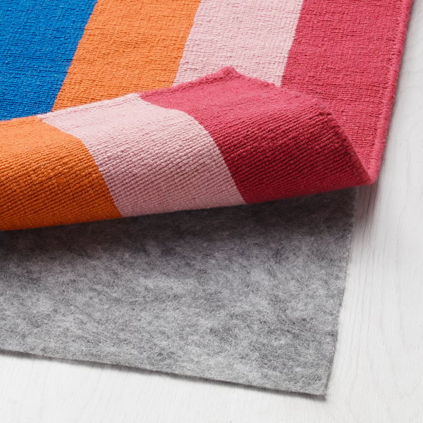 Colourful striped rug with felt backing laid on white floor.