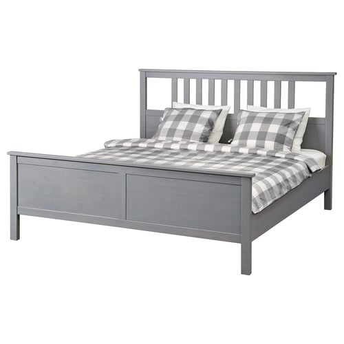 Grey HEMNES bed, wooden, rectangular, with neatly arranged chequered pillows.