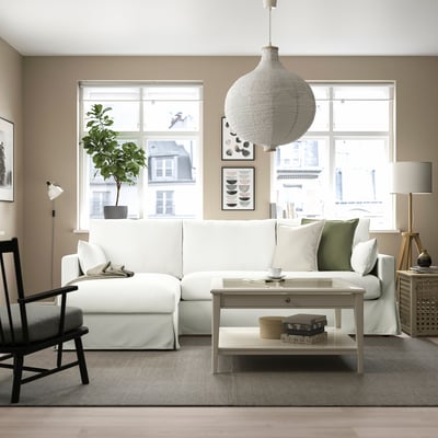 Cosy living room with HYLTARP sofa, chaise, pendant lamp, & windows. Black chair, coffee table, art & plant.