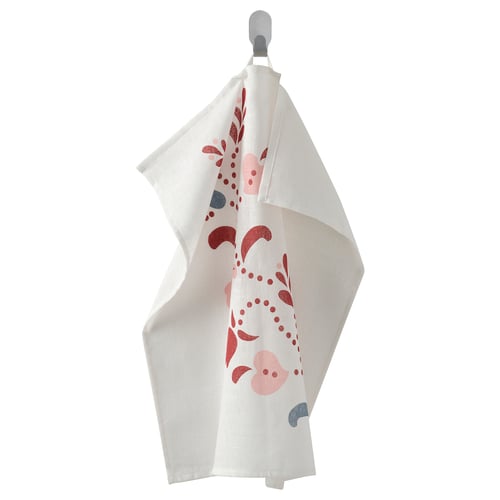 The INAMARIA towel, white with red and pink floral prints, hangs on a hook. Made of 100% cotton, its loop allows easy hanging.