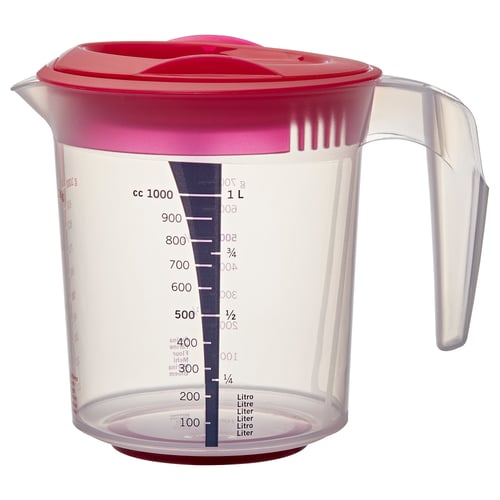 A red INFRIA measuring jug with a handle, marked with volume measurements in cc and litres. The jug has a clear body with a strainer in the spout.