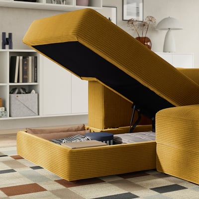 A yellow JÄTTEBO sofa with opened storage space reveals folded bedding and cushions inside, showcasing its space-saving design.