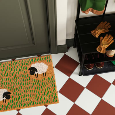 Doormat LÖGE playful sheep, fits well beside shoe rack, positioned near green cabinet.