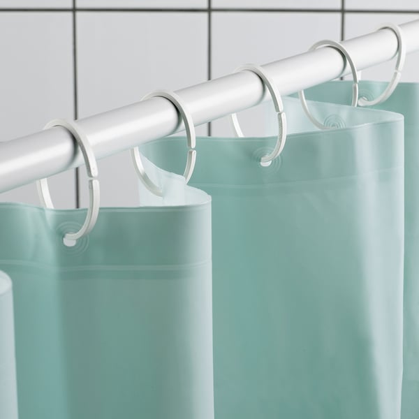 Two light green shower curtains hang from a silver rod with white hooks, demonstrating their water-repelling and durable design.