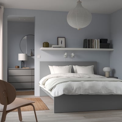 Grey bed with headboard, white pillows, blue wall, round mirror, dresser, lamp - minimalist scandinavian.
