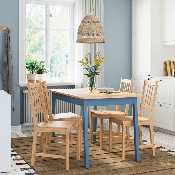 Bright kitchen with blue and wooden PINNTORP table, 4 chairs, yellow flowers, and a large window.