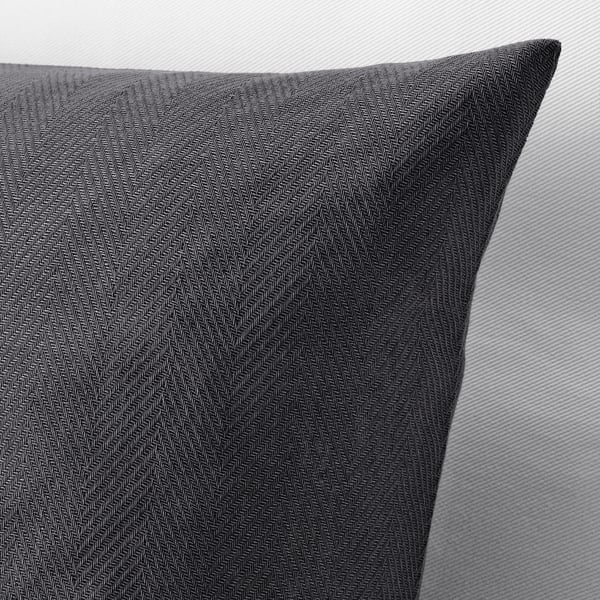 Dark grey pillow with herringbone pattern, neatly placed on a light sofa, showcasing high-quality cotton texture.
