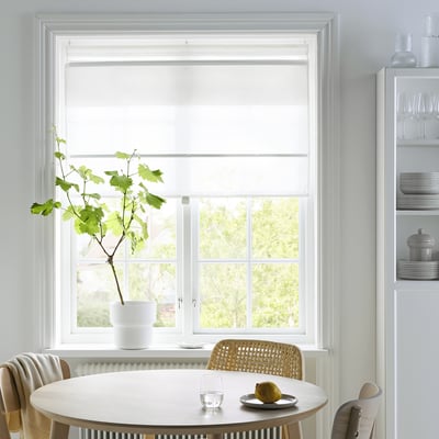 Modern dining area with RINGBLOMMA blinds, round table, woven chair, and potted plant.