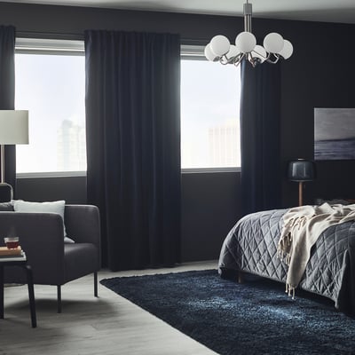 Modern bedroom with blue velvet curtains, a luxury bed, and minimalistic decor.