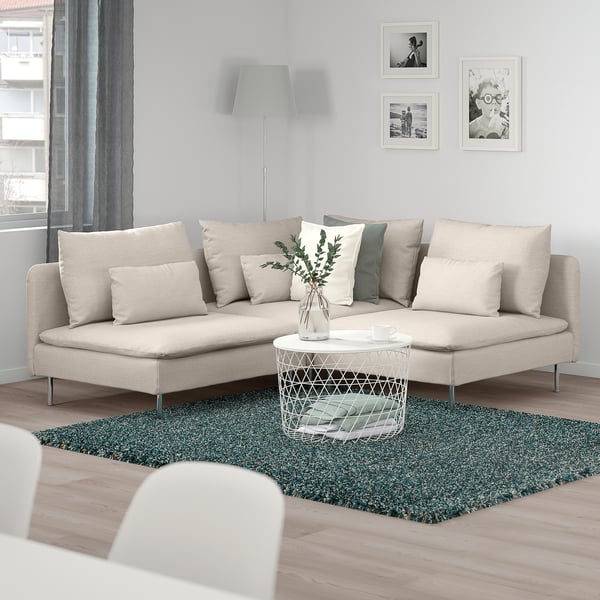 Beige SÖDERHAMN sectional sofa in cosy living area with dark rug, coffee table, plant, lamp, & photos.