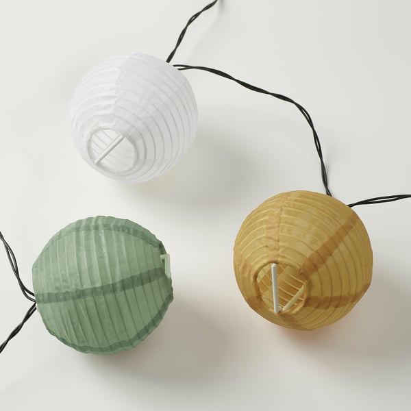 Three colourful lanterns on strings, white, green, and yellow, arranged on a white surface. High-quality materials and design for decorative lighting.