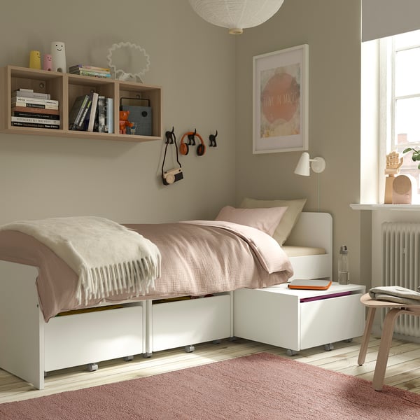 Cosy bedroom with soft pink rug, twin bed, and wall decor.