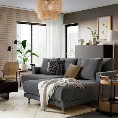 Modern grey UPPÅKRA sectional sofa, large, with cushions, blanket, near window.