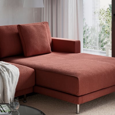 Red sofa with chaise, plush cushions, big window, cosy living room.
