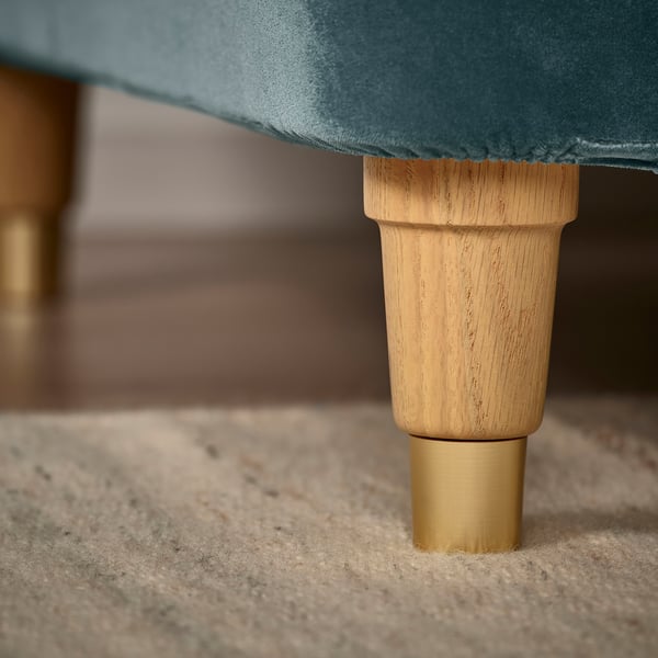 Upholstered seat leg detail: smooth wood, metal tip, fine fabric.