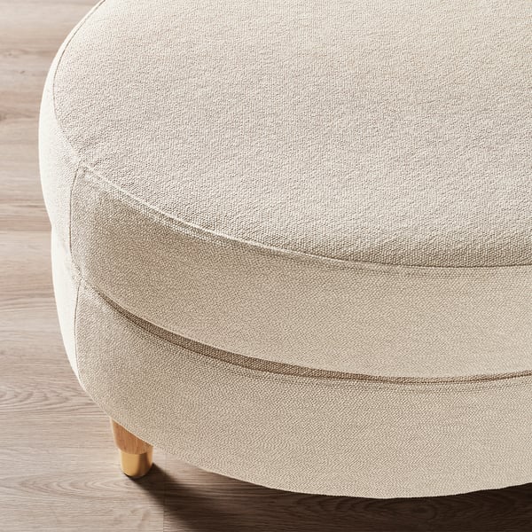A beige upholstered footstool with a cloth top and wooden legs.