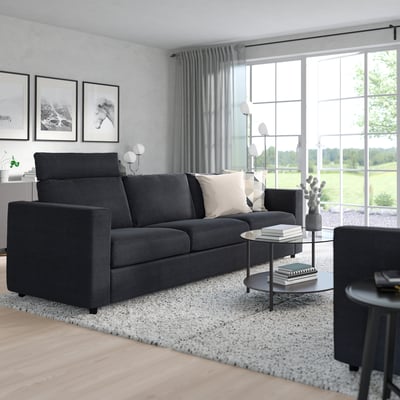 Modern living area with grey VIMLE sofa, black coffee table, and windows overlooking greenery.