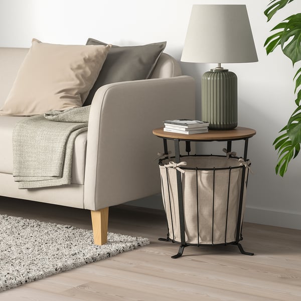 Angelsby side table beside sofa, rustic wood & metal, storage fabric bag, lamp & books.